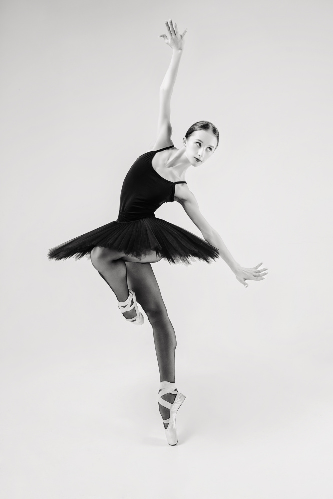 schwarzer Schwan. Ballerina im schwarzen Tutu zeigt Elemente des Balletttanzes in Bewegung von Alexandr