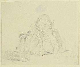 Am Tisch vor einem halb befüllten Glasgefäß sitzende Frau
