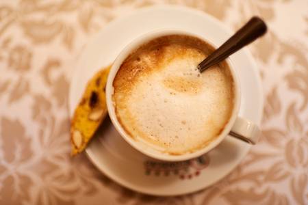 Eine Tasse Melange mit einer Cantuccini steht auf dem Tisch 2016